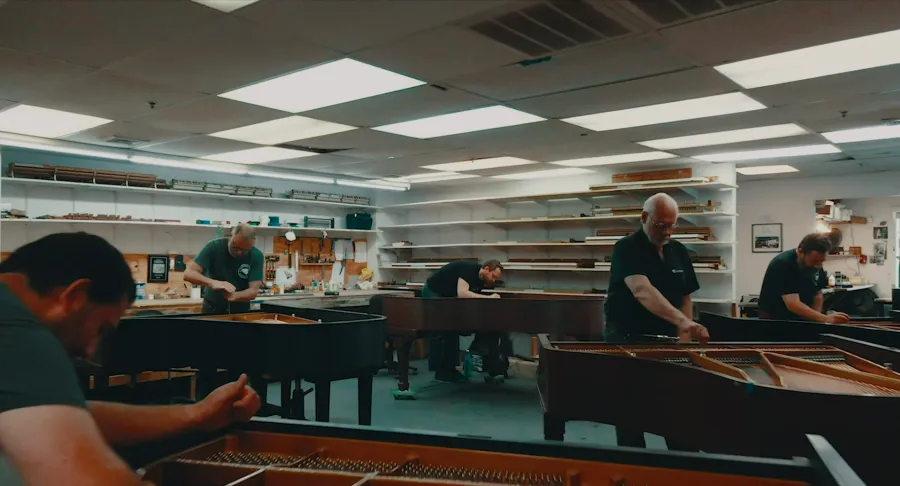Five craftsmen restoring grand pianos in the workshop